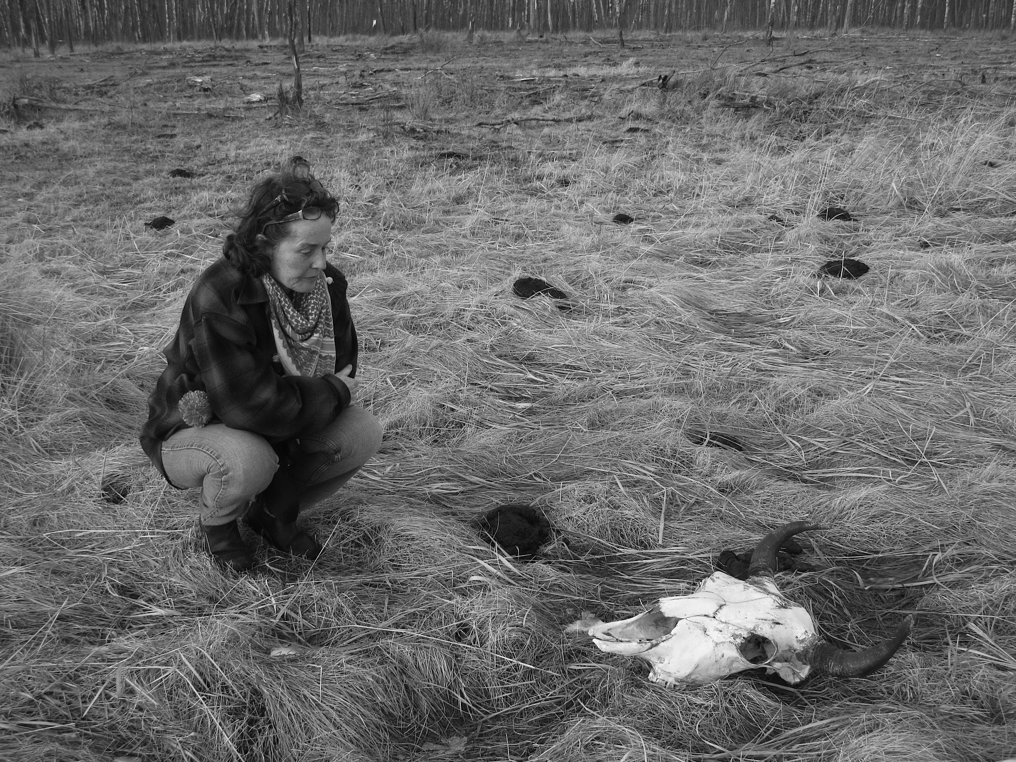 Christine Stewart crouches by a bison skull. 